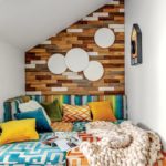 Reading nook featuring blue, orange, rainbow stripes and white cushions, and a wood-paneled wall