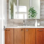 Wood bathroom vanity with white countertop and mirror hanging above