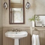 Power room featuring white pedestal sink, taupe wainscotting, white towel and agate sconces