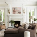 Cozy living room with a brown couch and a wood and marble fireplace