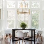 Bright dining area with large windows, black table and a brass and glass lighting fixture