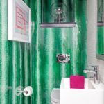 Powder room with white sink, white toilet, wallpaper that mimics malachite and a piece of modern artwork showing pink lines.