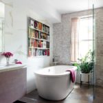 Master bathroom featuring stand alone bathtub, glass shower, potted plant and a photo of a bookcase above the bathtub.