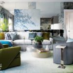 The condo's living room with a gray couch featuring throw pillows in shades of green, blue and gray. There's a green armchair and the walls behind the couch are mirrored.