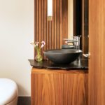 Powder room with walnut vanity, black bowl sink and white toilet