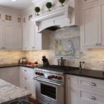 Mid-Cape Home Centers Kitchen with white cabinets, marble counters and a stainless steel oven with red knobs