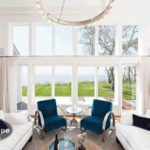 Mid-Cape Home Centers a sitting area with floor to ceiling windows with an ocean view and two blue sidechairs