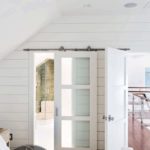 Room with white shiplap walls and a glass barn door