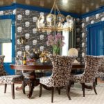 Dining room with blue trim and doors, and lotus-patterned wallpaper. There's a six-person wood dining table with chairs upholstered in a black, brown and white geometric pattern.