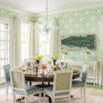 Dining rooms with patterned wallpaper in shades of pale blue, green and white. There's a glass chandelier hanging over the table.