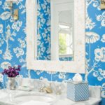 Close-up shot of a vanity with a mirror above it against bright blue wallpaper adorned with white flowers