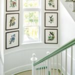 Stairwell with green rails with a window framed with framed bird prints