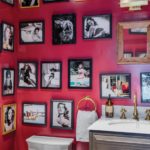 Powder room with red walls covered in black-framed photos