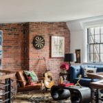 Julian Edelman's lounge with a brick wall adorned with a dart board. There's an acoustic guitar leaning up against the wall.