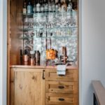 Recessed niche bar stocked with oranges, liquor and copper barware.