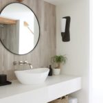Bathroom with exposed beams and a round mirror above a white porcelain sink