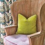 detail of a wood chair with a green accent pillow