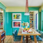 blue-green walls in the dining room with a wood table surrounded by six blue chairs