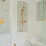 White tiled shower with gold fixtures