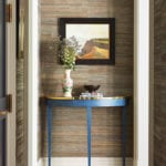 Hallway with grasscloth walls and blue demi-lune table