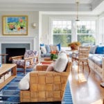 Coastal living room with rattan furniture and a blue rug.