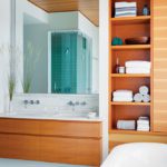 Contemporary bathroom with light wood, glass tiles, and a soaking tub.