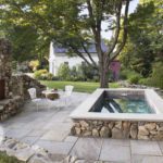 Plunge pool with a stone surround and slate patio