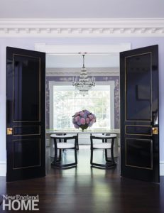 Shiny black doors opening up to a dining room.