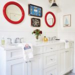 All white bathroom with round red mirrors