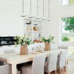 Light wood dining table with linen slip covered chairs.
