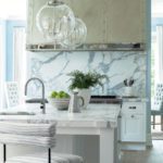 Kitchen rangewith large polished nickel hood and marble backsplash