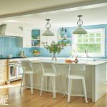 White kitchen with light blue backsplash and white pendant lights