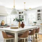 White kitchen with brown leather stools.