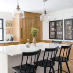 Kitchen with white island and black chairs.
