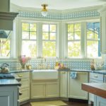 Kitchen with cream colored cabinets and a blue and white backsplash.
