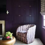 Corner of a dark bedroom with an upholstered chair,