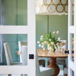 Dining room with green paneled walls and white drum chandelier