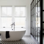 Freestanding tub on black and white patterned floor.