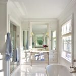 Large white bathroom with a freestanding tub and large mirrors.