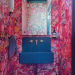 Powder room with a dark gray concrete sink and colorful wallpaper