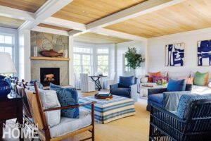 Comfortable Nantucket living room with a stone fireplace and light wood ceiling