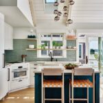 coastal kitchen with white cabinets and a sage green back splash