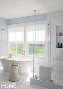 White soaking tub placed in front of a window with a coastal view.