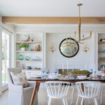 A coastal dining room with a dark wooden table and white chairs