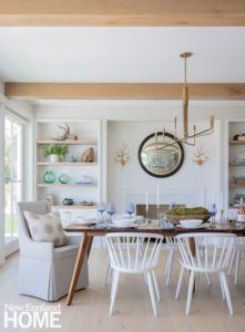 A coastal dining room with a dark wooden table and white chairs