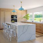 Sunny kitchen with oak cabinetry and quartz countertop.