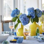 Table setting with yellow vases and blue hydrangeas