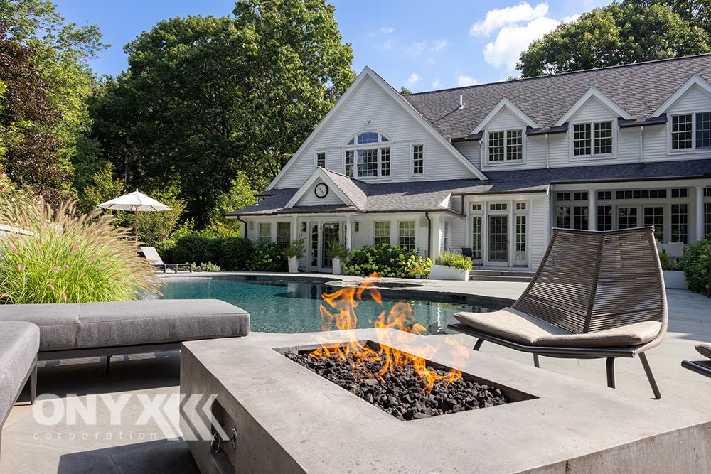 Traditional white home with swimming pool and fire pit.