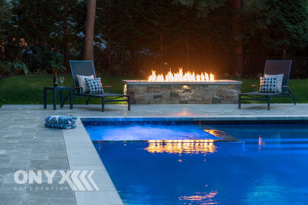 Rectangular swimming pool and fire pit at twilight.