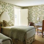 Guest bedroom with floral wallpaper and an upholstered headboard.